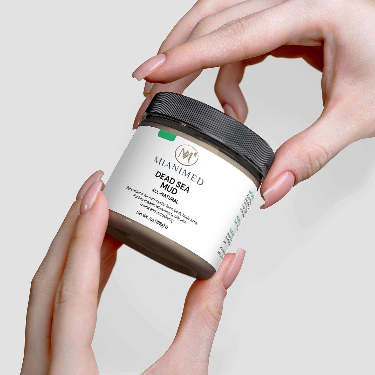 MIANIMED Premium Dead Sea Mud skincare product being held by two hands.