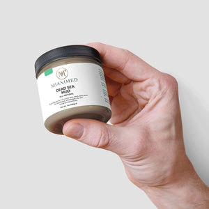 Hand holding MIANIMED Premium Skincare Dead Sea Mud Jar