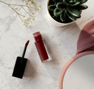 MIANIMED premium skincare red lipstick on marble surface with flowers and green succulent plant