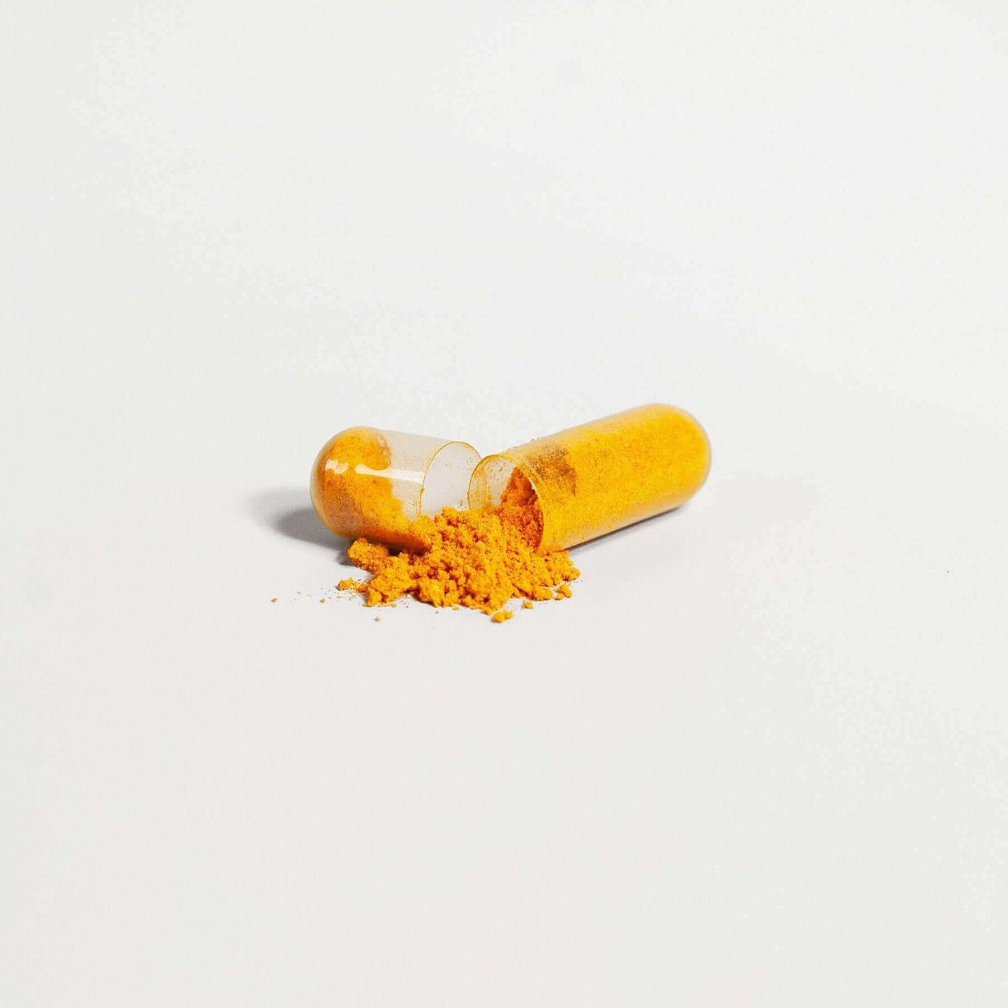 Open yellow capsule with powder spilling out on white background, representing MIANIMED premium skincare supplement.