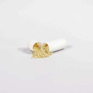 Open white capsule with spilled yellow powder on neutral background, representing MIANIMED premium skincare product.