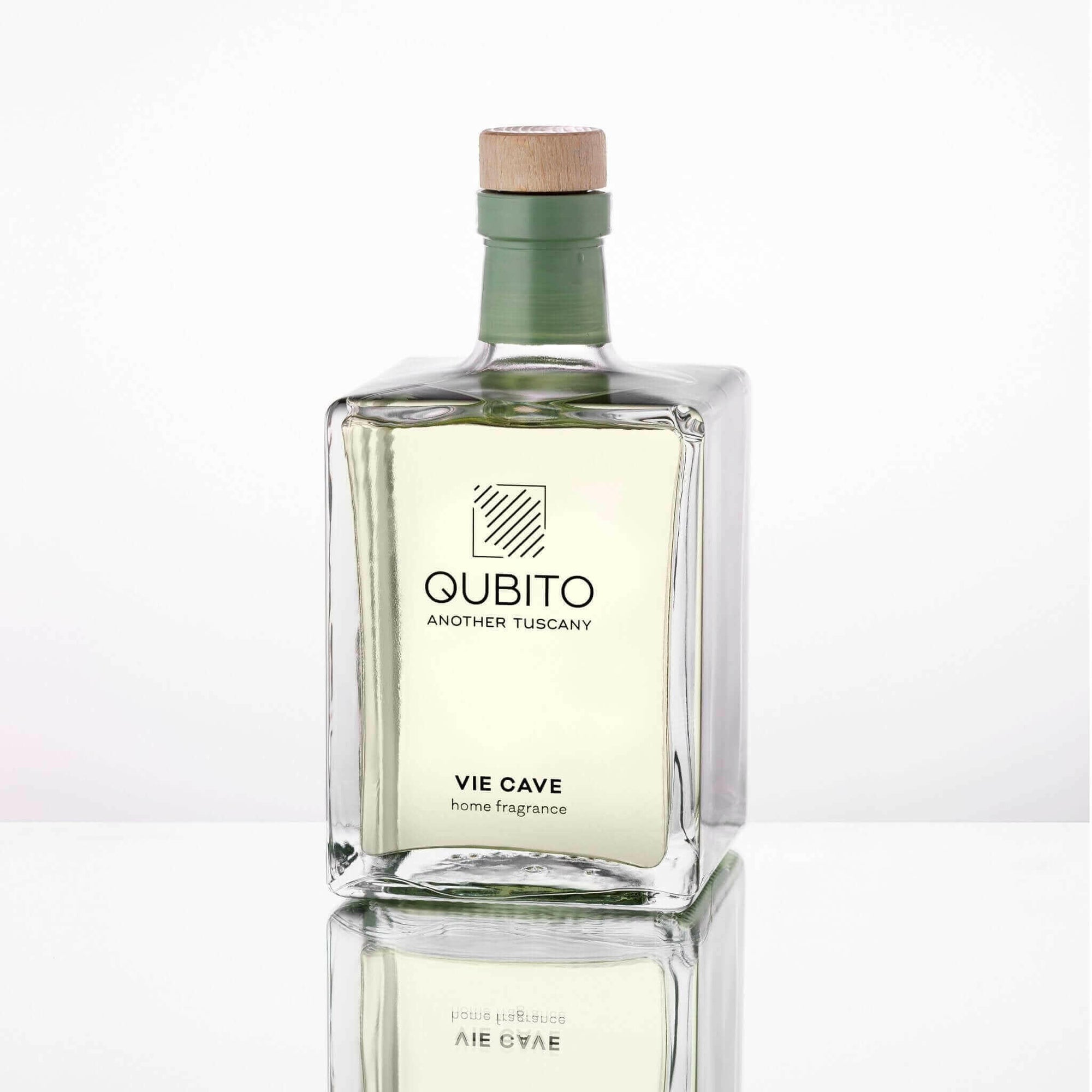 Qubito Another Tuscany Vie Cave home fragrance bottle with green liquid and wooden cap on a reflective surface.