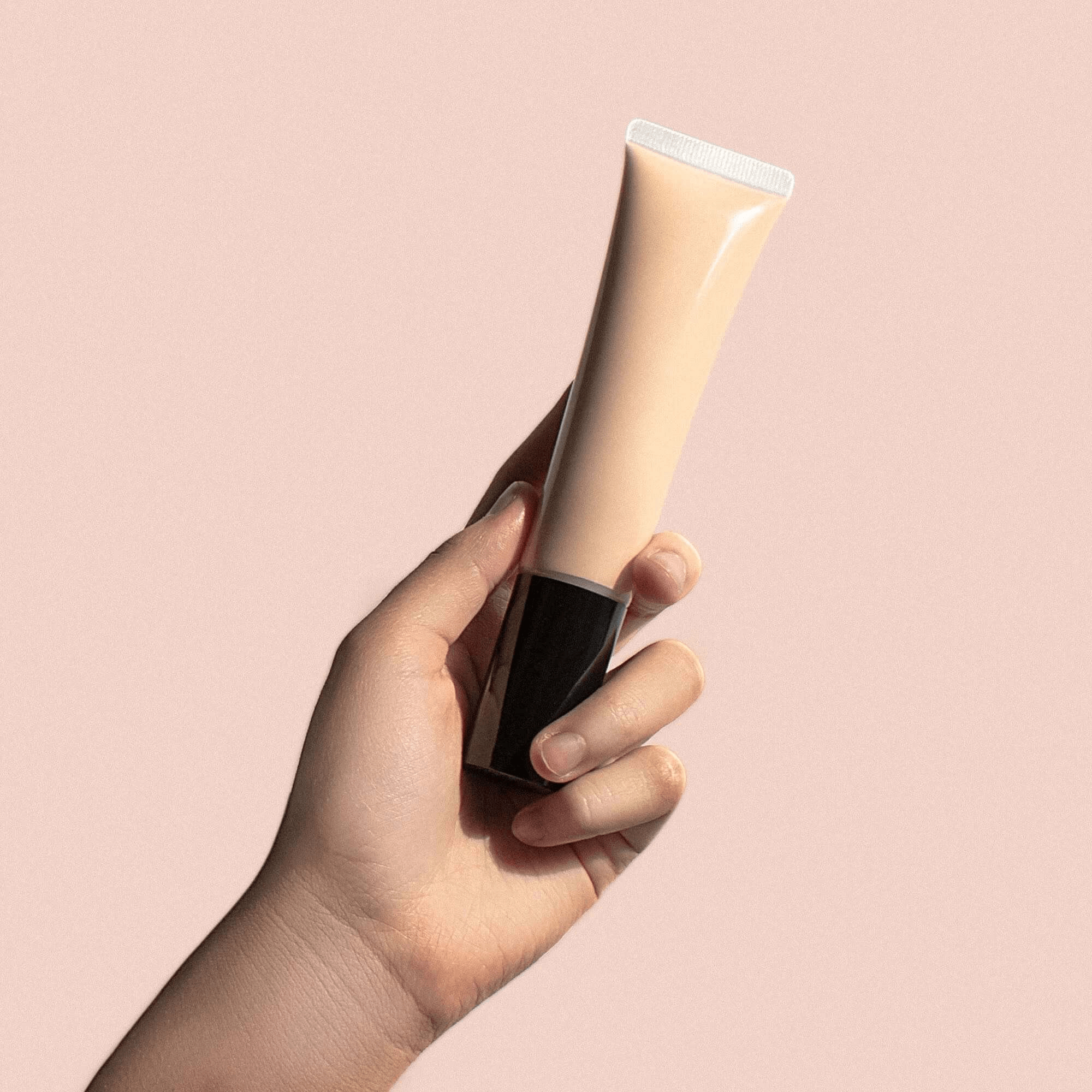 Hand holding MIANIMED premium skincare tube against a pink background.