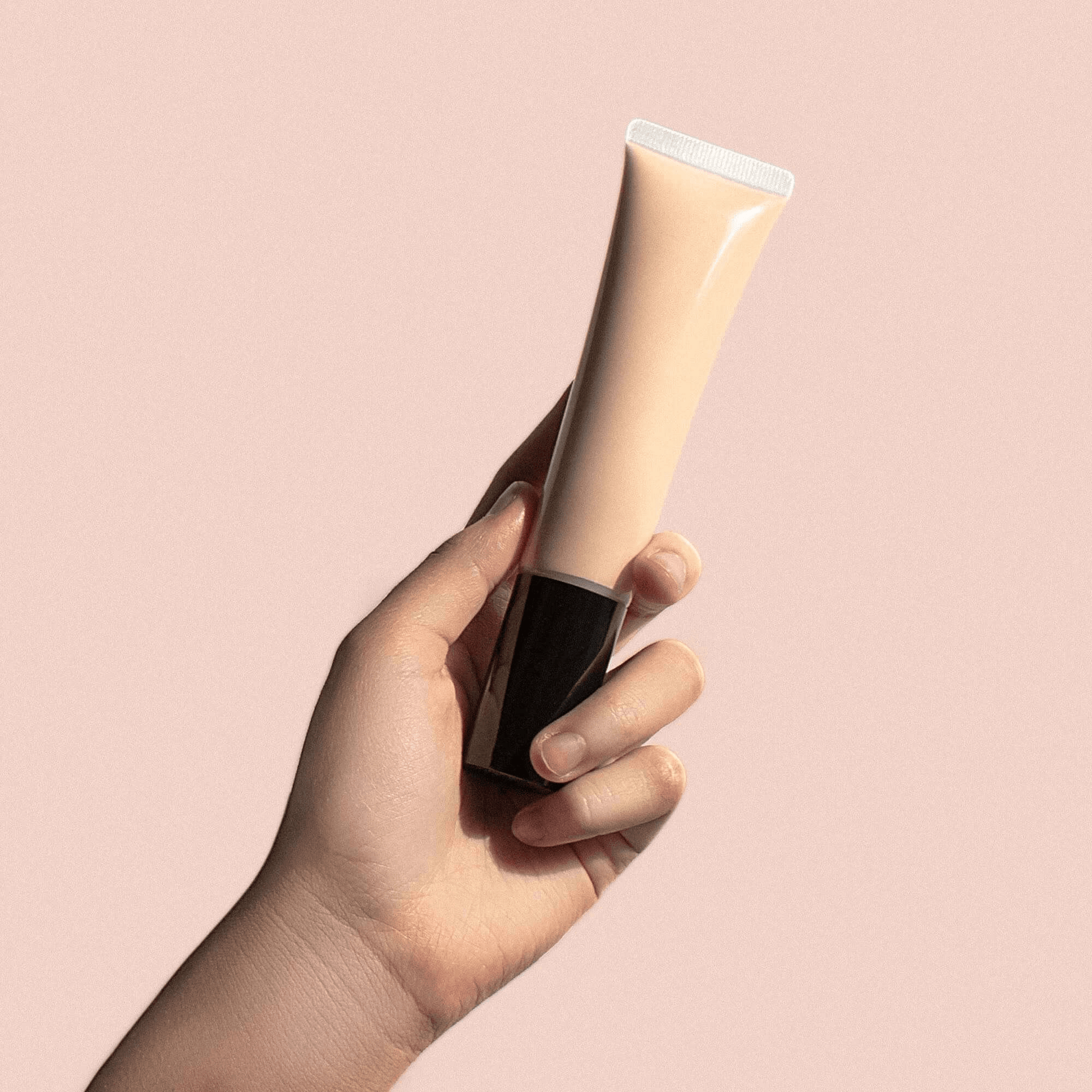 Hand holding MIANIMED premium skincare tube against a neutral background.