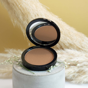 Premium MIANIMED skincare compact powder with mirror placed on a stylish concrete stand.