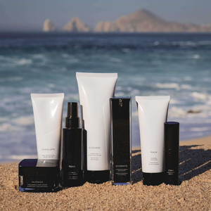 Assorted MIANIMED premium skincare products displayed on a beach with ocean and mountains in the background